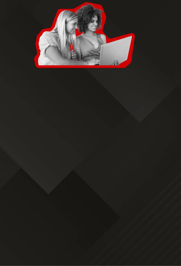 Zwei Frauen lächeln während sie auf den Laptop schauen.