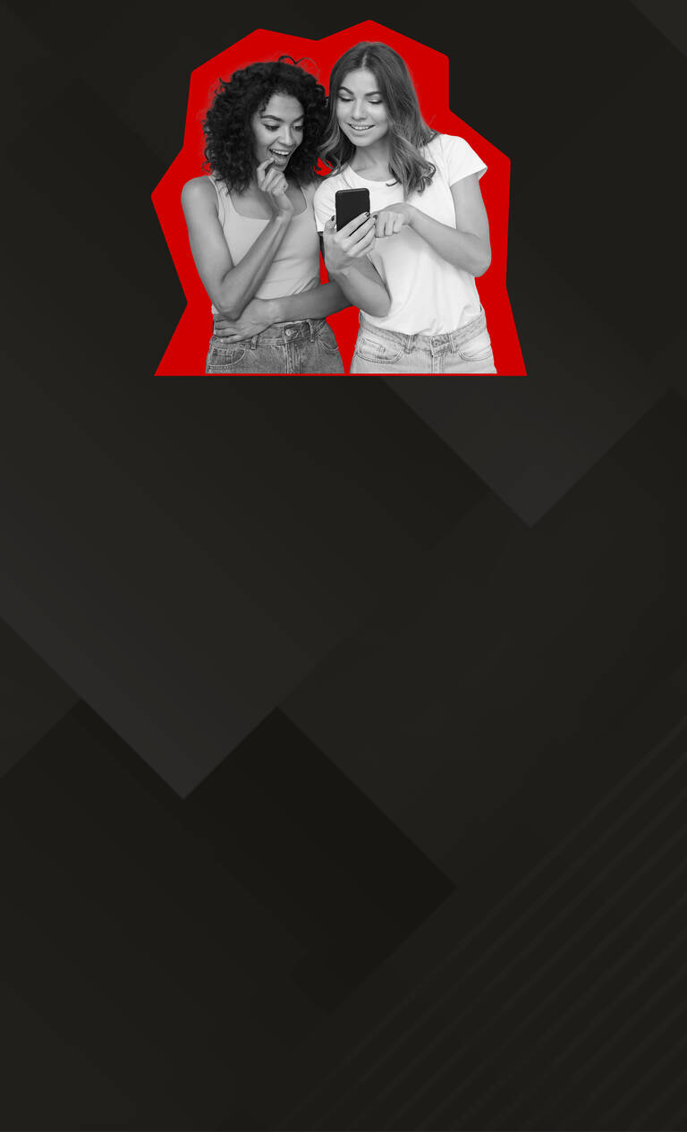 Zwei Frauen stehen lächelnd nebeneinander und schauen auf ihr Handy