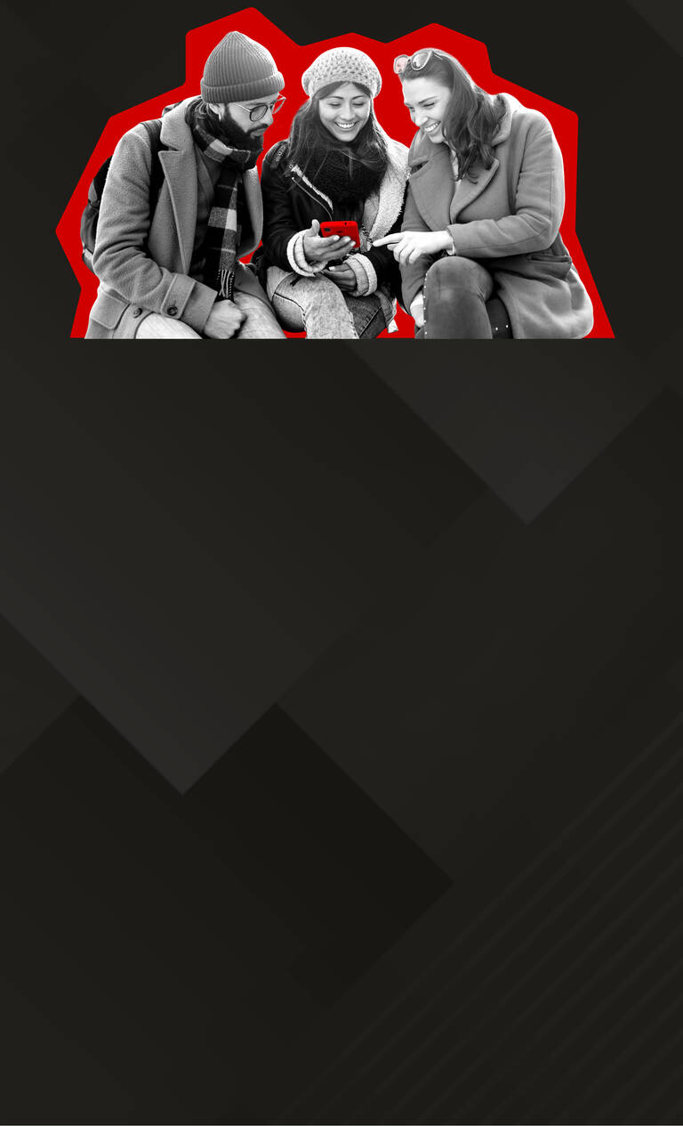 Zwei Frauen stehen lächelnd nebeneinander und schauen auf ihr Handy