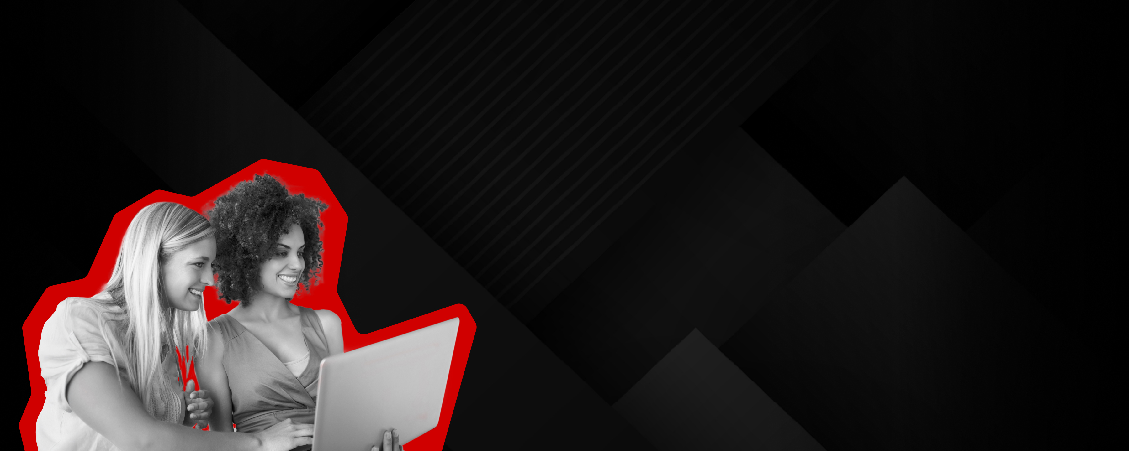 Zwei Frauen lächeln während sie auf den Laptop schauen.